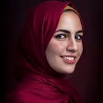 Stunning profile portrait of a woman wearing a red hijab, showcasing beauty and elegance.